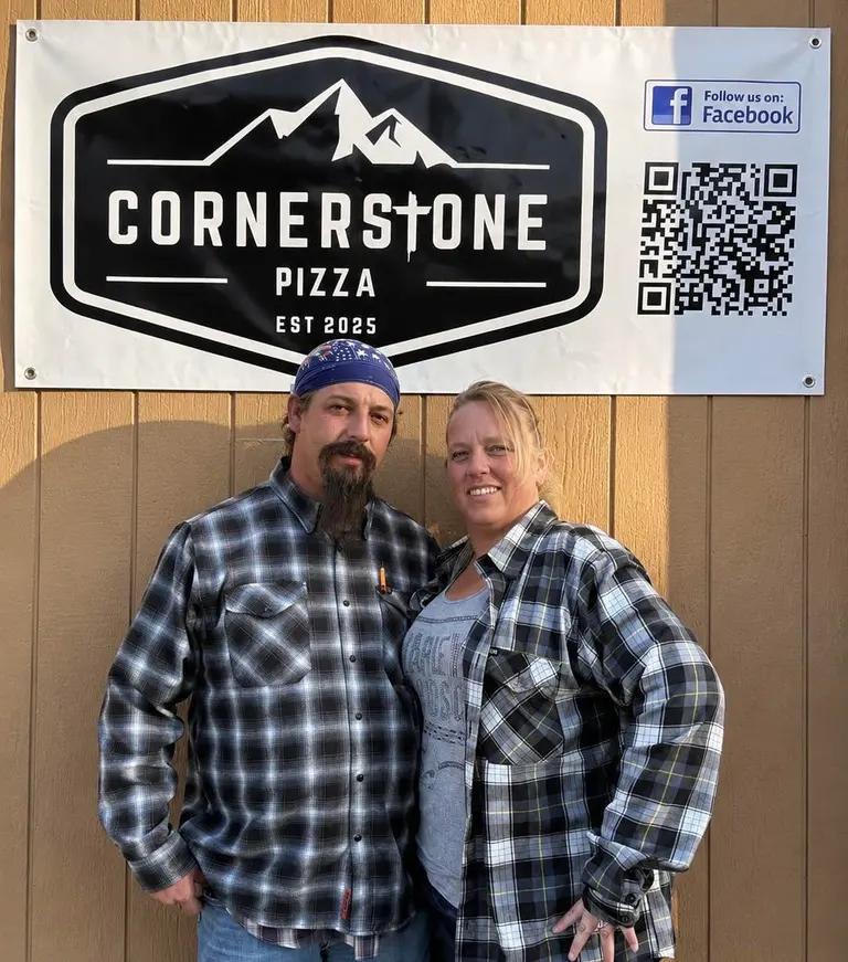 Heather and Stephen Baxter standing under the Cornerstone Pizza banner at the cart.